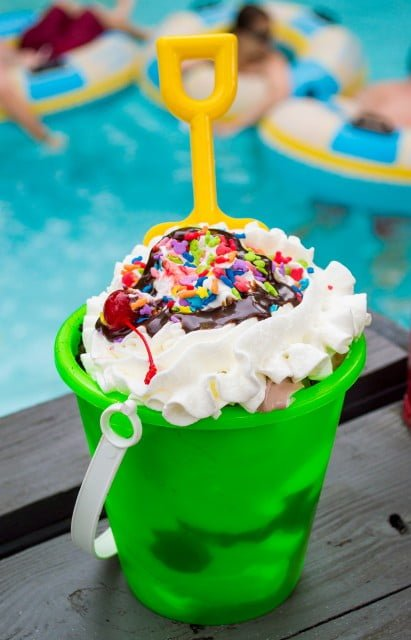 A large sand pail sundae from Happy Landings Ice Cream at Disney's Typhoon Lagoon, filled with layers of vanilla and chocolate soft serve ice cream, topped with whipped cream, sprinkles, and a cherry